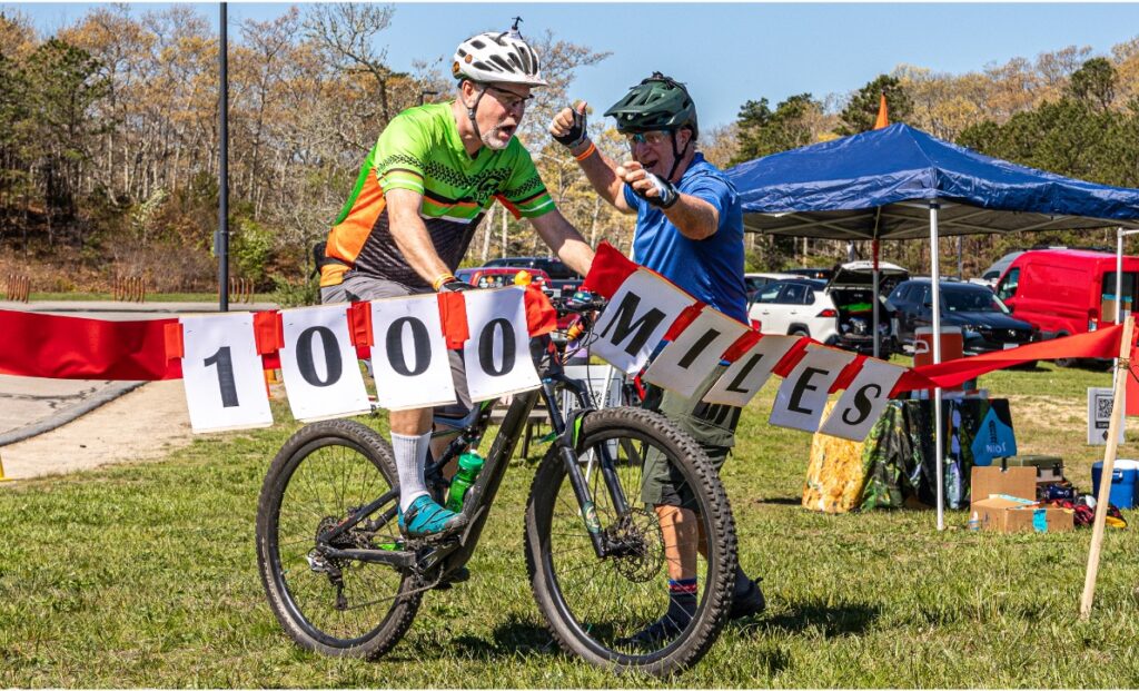 Mountain Biker breaking through a thousand mile banner